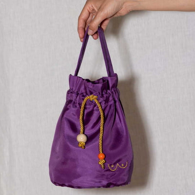Main qui tient un sac Mamatich aubergine avec Boobs de Gapianne